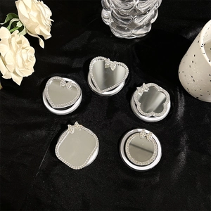 Detailed view of assorted rhinestone mirrored phone grips with bows on black velvet