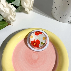 Macro detail of round phone grip with floral painting on a pastel ceramic tray