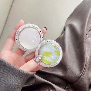 Handheld view of a round magnetic phone grip with a glass finish and white cloud pattern
