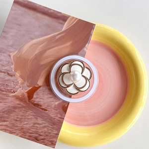 Detail view of a white camellia magnetic phone grip with gold edges and pearl center
