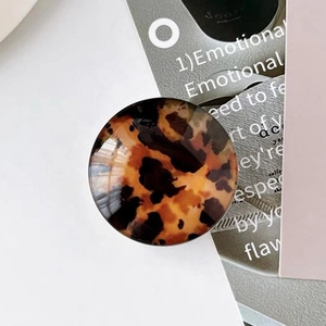 Macro view of a round tortoiseshell phone grip with amber patterns and glossy finish