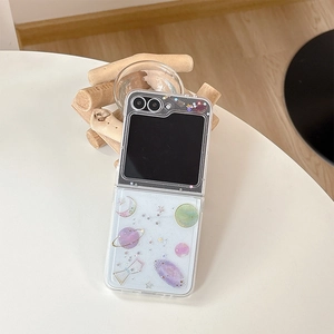 Dettaglio custodia Galaxy Z Flip 6 con glitter pianeti e luna su supporto in legno