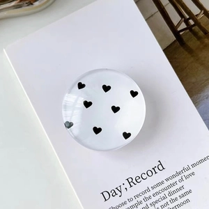 Close-up of circular magnetic phone grip with minimalist black heart and white base