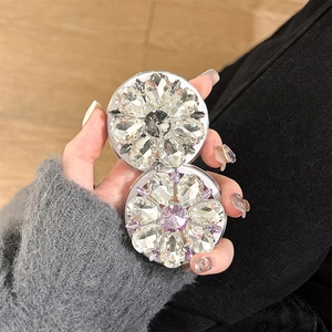 Detail of luxury rhinestone flower magnetic phone grip and mirror held in hand
