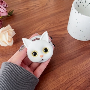 Close-up of white cat phone socket grip with Gift For You print on a wooden desk