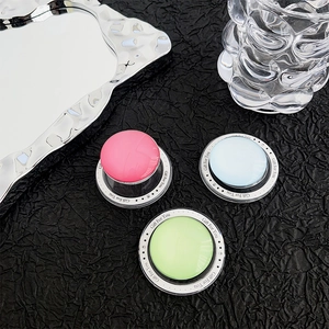 Detail of magnetic round phone holders in pink, blue, and green on a dark textured surface