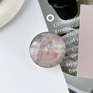Top view of a round aurora marble phone grip with iridescent pink and green textures
