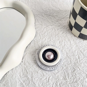 Close-up of circular phone grip with pink pearl center and Gift For You lettering