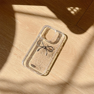 Custodia iPhone trasparente glitterata con fiocco in metallo argento su legno chiaro