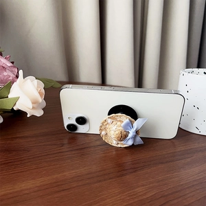 Straw hat phone socket with bow and pearls on a white smartphone on a desk