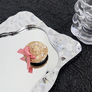 Detail of a straw hat phone grip with a pink silk bow and white pearls on a tray