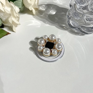 Detailed macro view of a floral MagSafe grip with white pearls and sparkling rhinestones