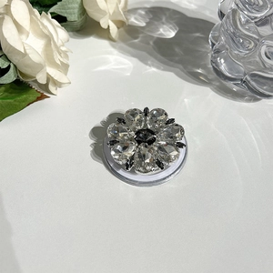 Close-up of sparkling rhinestone flower MagSafe grip with clear base on white surface