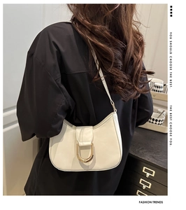Detail of white cream hobo bag with gold U-shaped hardware shown on a model's shoulder