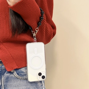 Clear MagSafe phone case with black beaded wrist strap worn by a person in a red sweater