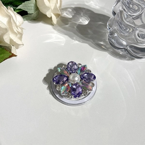 Detail of petal-shaped MagSafe phone grip with purple rhinestones and central pearl