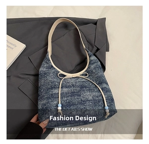 Detailed close-up of blue denim hobo bag with beige bow and contrasting beads