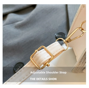Detail of adjustable white leather shoulder strap with polished gold hardware and lobster clasp