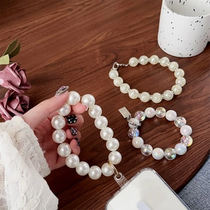 Close-up of handmade pearl and iridescent beaded phone charms with metal clasps