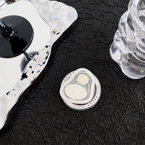 Close-up of a 3D heart-shaped gem phone grip on a sleek black pleated surface