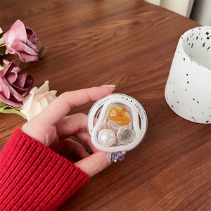 Detail of magnetic phone grip featuring white pearls and amber resin on a wooden desk