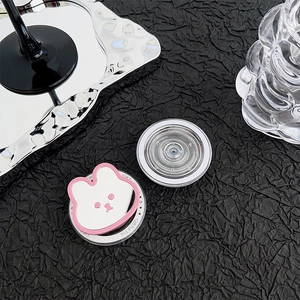 Détail du support téléphone lapin rose et poignée minimaliste claire sur tissu noir