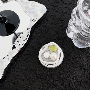 Detail showing an irregular silver frame phone grip with green gemstone and pearl inlay