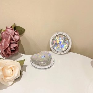 Close-up of heart and round laser sequin phone grips on a table with roses