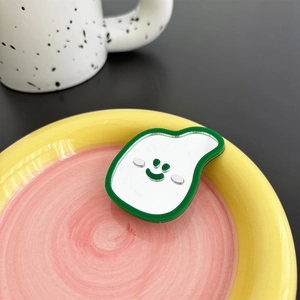 Close-up of a green-bordered mirror phone socket with a smiling face on a ceramic plate