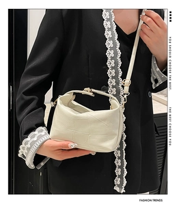 Close-up of beige leather crossbody bag with gold hardware and lychee grain texture