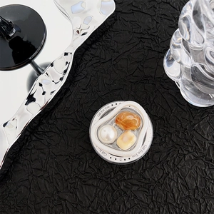 Detailed view of a circular phone socket featuring pearls and amber-colored gemstones