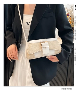 Detail of white and beige leather crossbody bag with crocodile texture and gold clasp