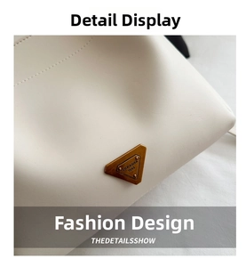 Macro detail of antique gold triangle logo on cream white leather shoulder bucket bag