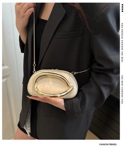 Detail of elegant cream oval clutch with gold ring handle and metal chain strap