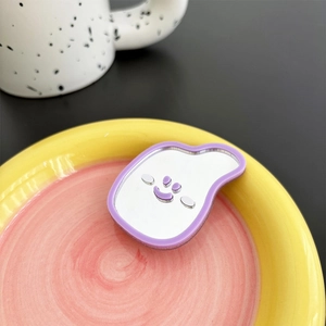 Detail of creative purple smiley face mirror phone grip on vibrant colorful table