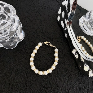 Detail of elegant white pearl phone wristlet with gold rhinestone spacers and lobster clasp