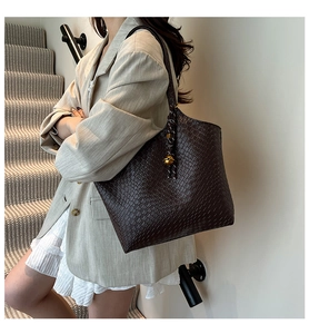 Détail du sac cabas marron foncé avec texture tressée et breloque dorée sur le mannequin