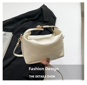 Detail view of lychee-textured beige handbag featuring block stitching and gold hardware