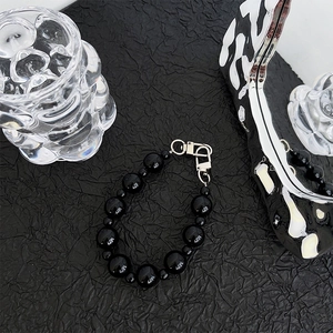 Close-up of a minimalist black beaded phone strap with high-gloss finish and silver clasp