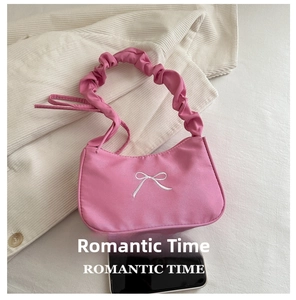 Top view of pink silk baguette bag with white bow embroidery and scrunchie handle