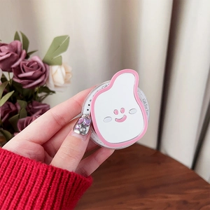 Close-up of pink and white cartoon smiley face phone grip on a wooden table