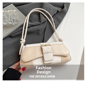 Detail of cream shoulder bag featuring faux crocodile texture and gold metal clasp