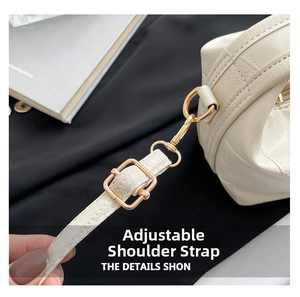 Detail of adjustable strap with gold metal buckle on white lychee leather bag