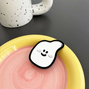 Cute ghost shaped mirror phone grip displayed on a vibrant pink and yellow tray