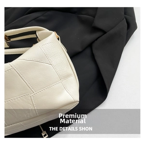 Close-up of beige lychee grain leather stitching detail on minimalist shoulder bag