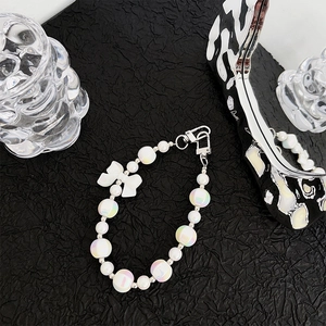Detail of pearlescent beaded phone strap with a white bow and silver lobster clasp