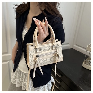 Detail of a beige woven mini crossbody bag with leather trim and decorative fringe