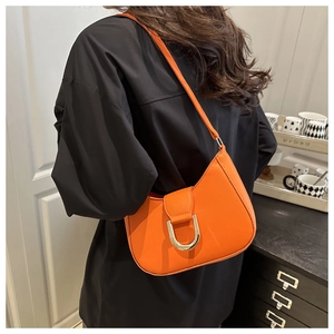 Detail of a bright orange shoulder bag with a gold horseshoe buckle on black shirt