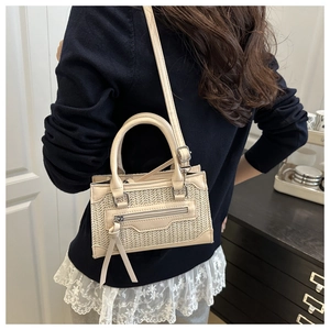 Detailed back view of a cream woven leather crossbody bag worn by a model