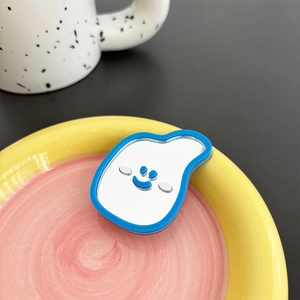 Close-up of a blue cloud-shaped mirror phone grip with a smiley face on a ceramic tray